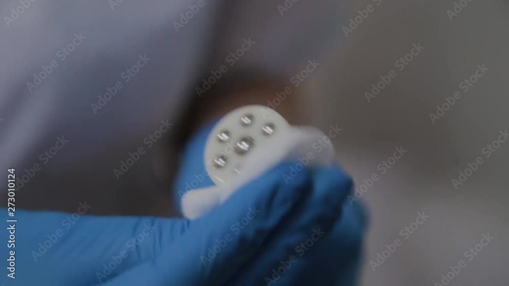 A professional cosmetologist treats the device for microcurrents in the cosmetology cabinet with an antiseptic. A professional cosmetologist treats the device for microcurrents in the cosmetology cabinet with an antiseptic.