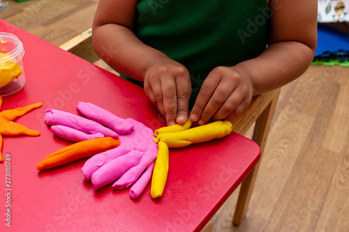improving fine motor skills educational games concept, modeling soft clay plasticine children's hands close-up red background