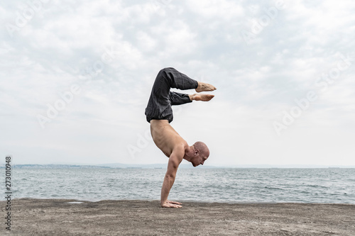 Fototapeta Man practicing yoga handstand outdoors