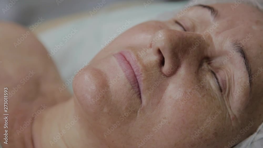 An elderly woman is lying on a couch in a cosmetology clinic. An elderly woman is lying on a couch in a cosmetology clinic.