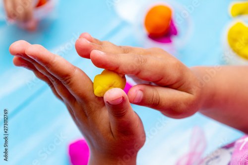 improving fine motor skills educational games concept, modeling soft clay plasticine children's hands close-up blue background