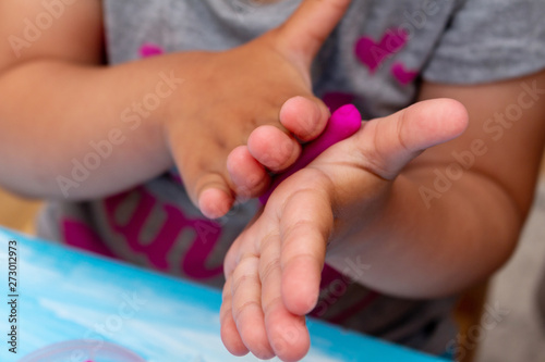 improving fine motor skills educational games concept, modeling soft clay plasticine children's hands close-up blue background