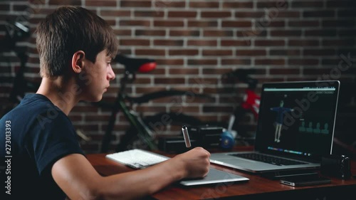 Freelance teen 3d illustrator, content maker, working 3d modelling program and creates a character for further animation on the laptop in house office.