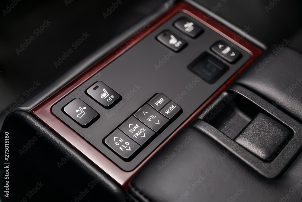 Сlose-up of the car  black interior:   seat heatting and adjustment, volume, true track  buttons,  temperature regulator and other buttons. Soft focus