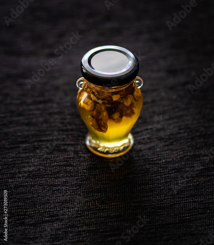 honey with walnuts in a jar from Greece on a black background