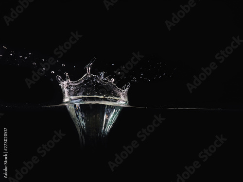 Splash of water isolated on black background, close up view. Drop of water makes splash on surface, background for overlays design, screen blending mode layer