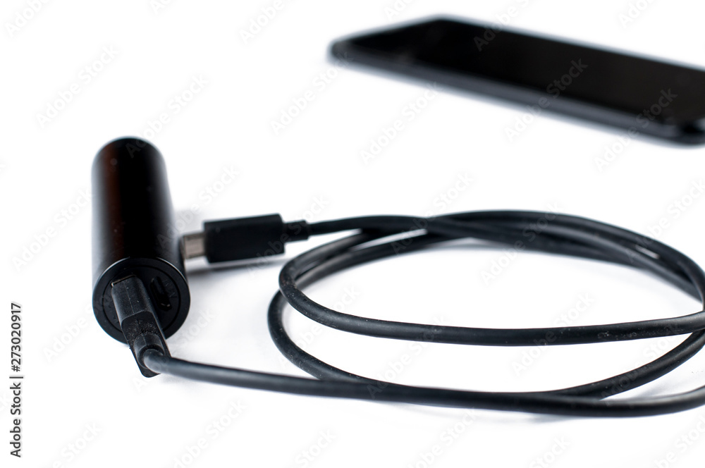 Black mobile phone and charger isolated on white background.Copy space