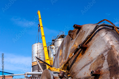 Rusted huge metal silos are placed on the ground for cutting to scrap steel