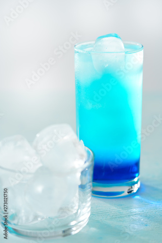 Blue Lagoon cocktail is a collins glass. Light blue background, real ice, high resolution
