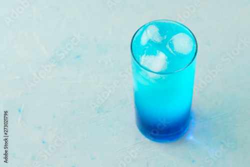 Blue Lagoon cocktail is a collins glass. Light blue background, real ice, high resolution