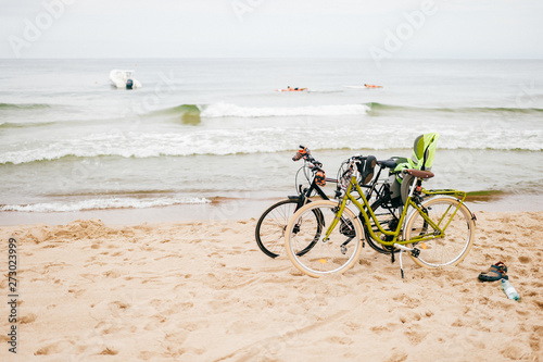 Two bicycles stand on beach against sea