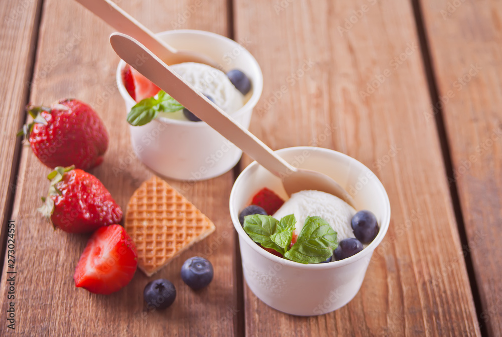 Vanilla ice cream with waffles, mint leaf, strawberries and blueberries on the wooden table Vanilla ice cream with waffles, mint leaf, strawberries and blueberries on the wooden table