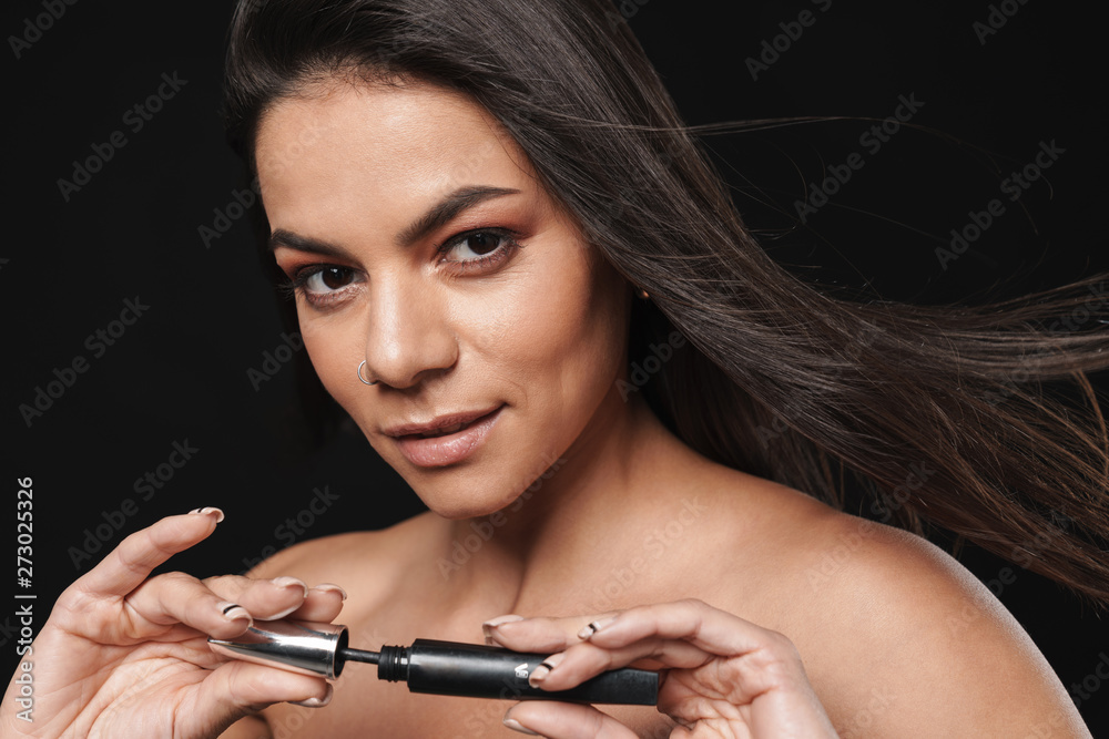 Beautiful naked woman posing isolated over black wall background holding mascara apply makeup. Beautiful naked woman posing isolated over black wall background holding mascara apply makeup.