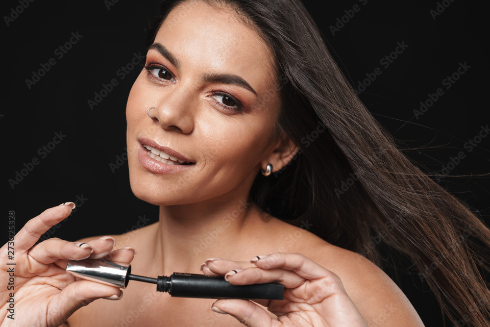 Beautiful naked woman posing isolated over black wall background holding mascara apply makeup. Beautiful naked woman posing isolated over black wall background holding mascara apply makeup.