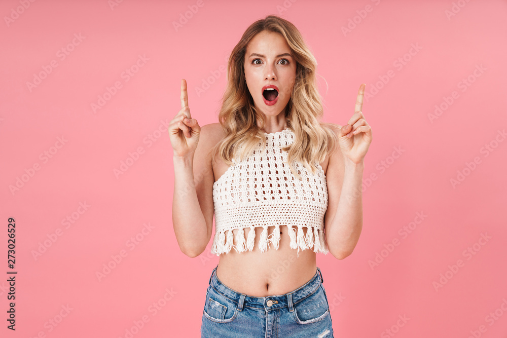 Shocked young excited woman posing isolated over pink wall background pointing. Shocked young excited woman posing isolated over pink wall background pointing.