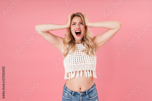 Shocked young excited woman posing isolated over pink wall background.