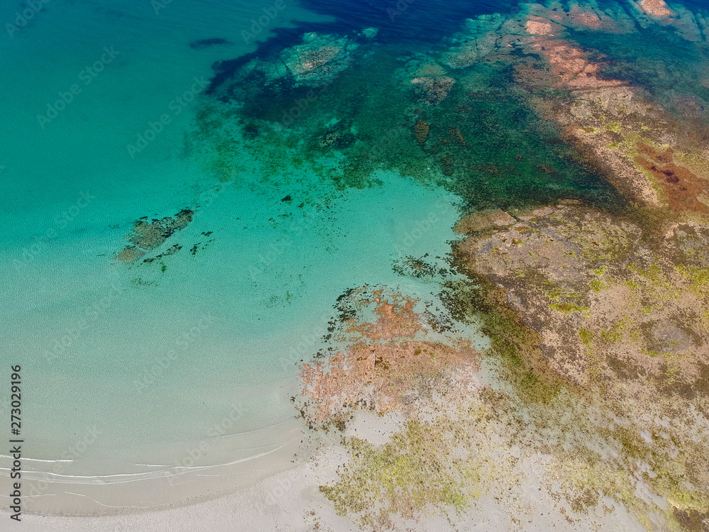 Aerial view of wonderful beach with white sand and turquoise water, with some rocks  underwater and few people swimming. Aerial view South coast of Guernsey island, UK, Europe.