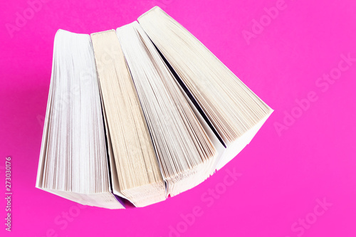 Books stand in a row on a bright pink background. The concept of reading, new books, libraries, book business. Flat lay, minimalism, top view. Copy space.