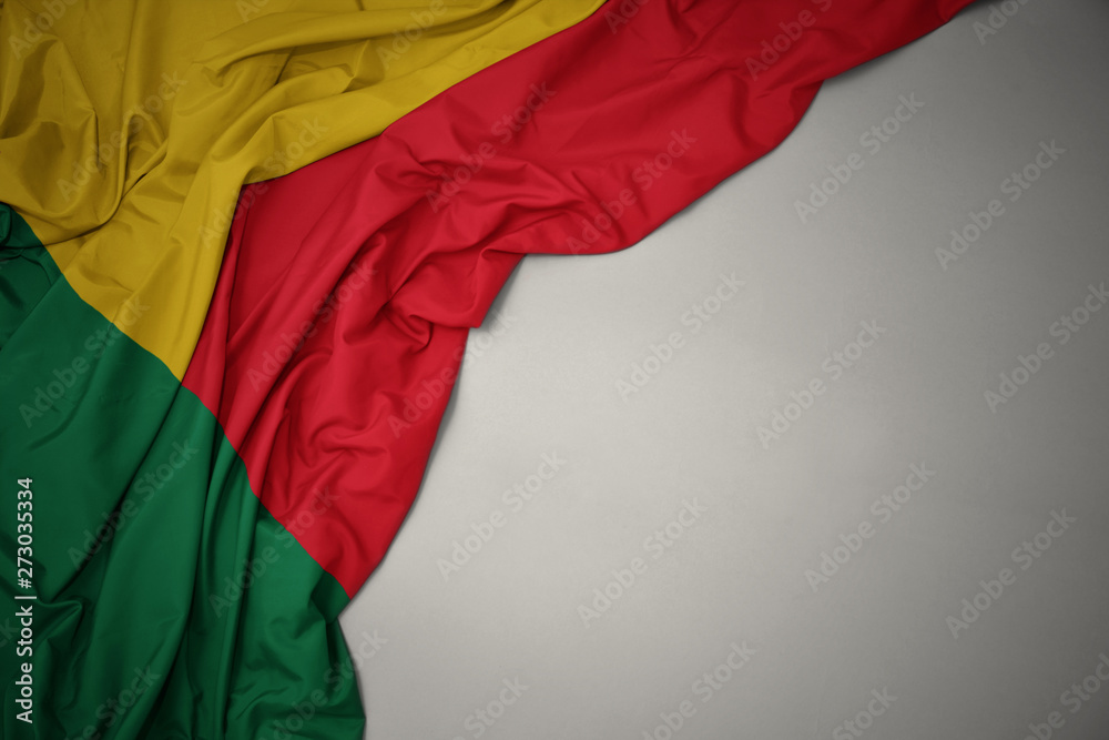 waving national flag of benin on a gray background.