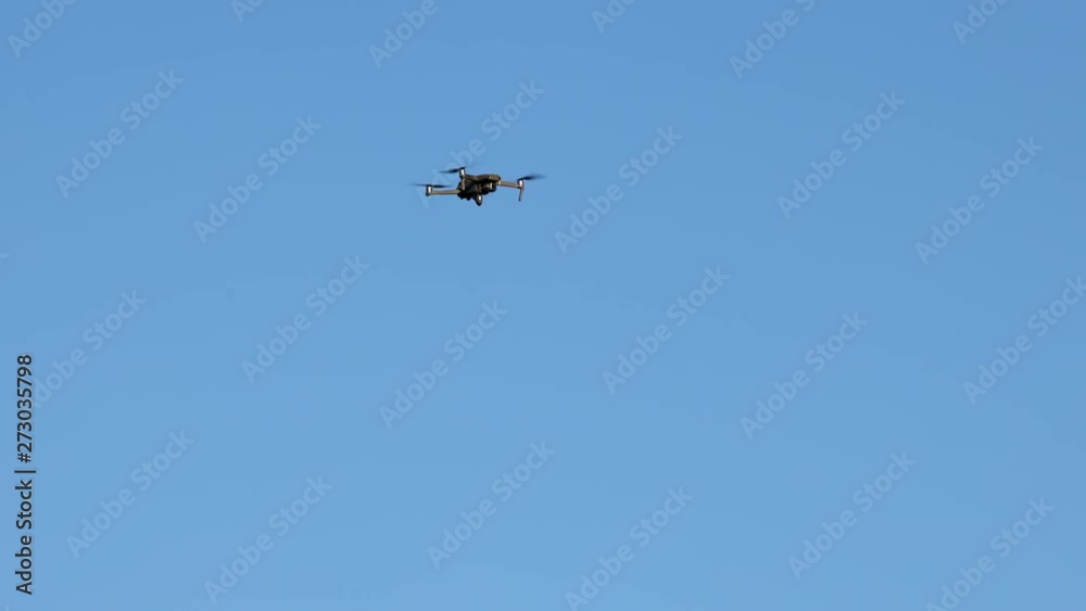 Hovering drone being swarmed, attacked by cliff swallow birds. Isolated on blue sky background. Hovering drone being swarmed, attacked by cliff swallow birds. Isolated on blue sky background.