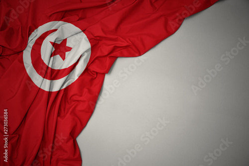 waving national flag of tunisia on a gray background.