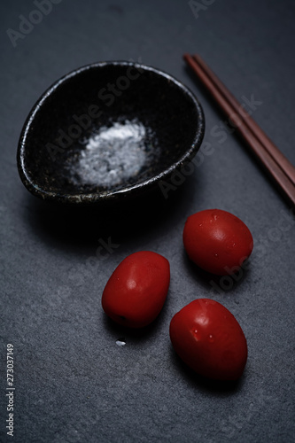 A Cherry Tomato, chopstick & ceramic bowl Soy Sauce on black slate stone