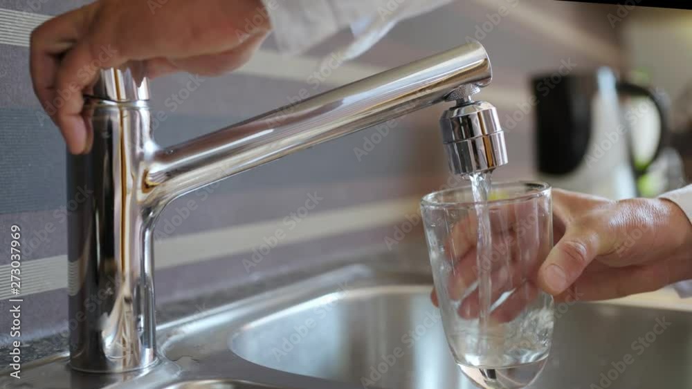Pouring Fresh Tap Water Into a Glass - Close up of man hands, pouring glass of fresh water from tap in kitchen