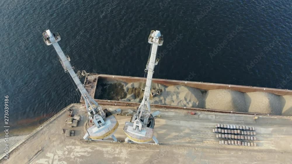 Modern cranes work at docks, moving breakstones from a barge. Modern cranes work at docks, moving breakstones from a barge.