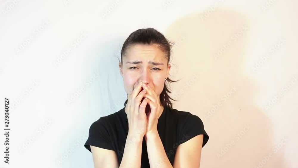 Young beautiful girl is very upset. The face expresses disappointment and sadness. The girl covers her face with her hands and cries. Portrait on white background Young beautiful girl is very upset. The face expresses disappointment and sadness. The girl covers her face with her hands and cries. Portrait on white background