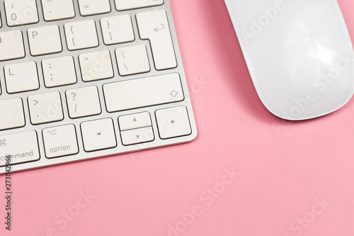 Pink office desk background with computer keyboard and other office supplies. Top view with copy space, flat lay.