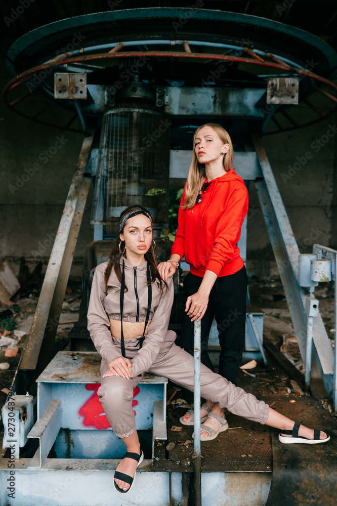 Stylish female couple posing at abandoned cableway station