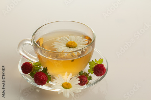 cup of herbal tea with chamomile flowers on a white table