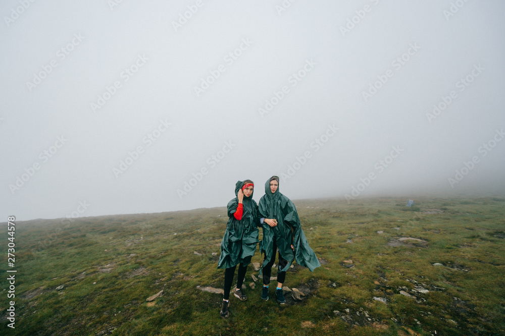 Happy female couple hikers posing in foggy mountains.