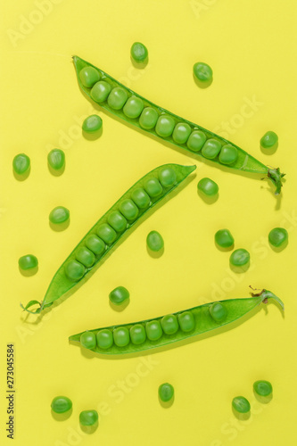 Fresh green pea pods and peas on the yellow background.
