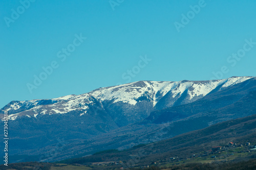 Last snow in the mountains in early spring against a clean blue sky.