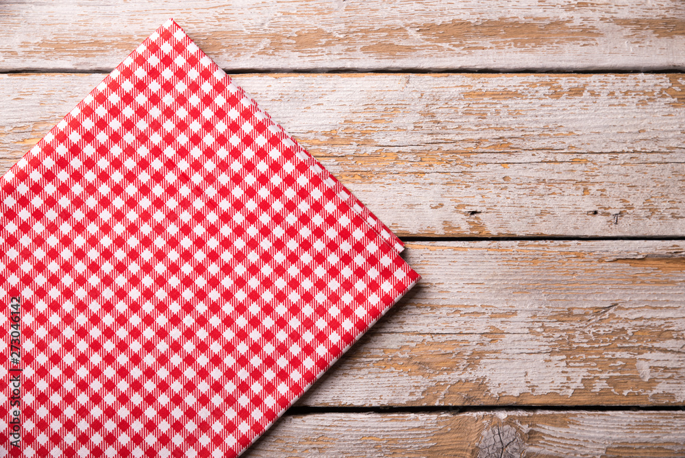 Empty wooden deck table and red checked tablecloth over mint wallpaper background Empty wooden deck table and red checked tablecloth over mint wallpaper background