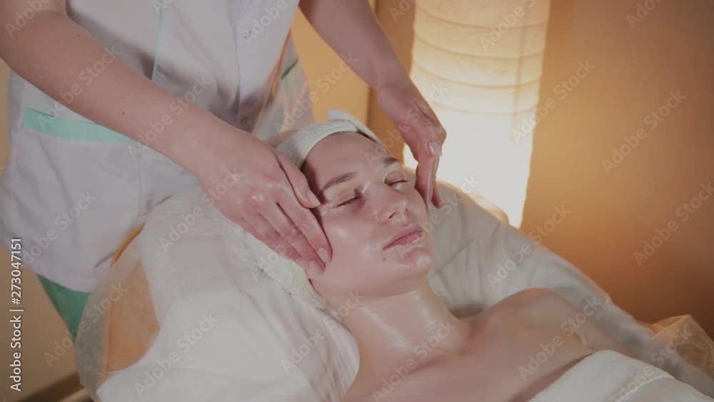 Professional beautician makes a complex massage to a young girl in the cosmetology office. Professional beautician makes a complex massage to a young girl in the cosmetology office.