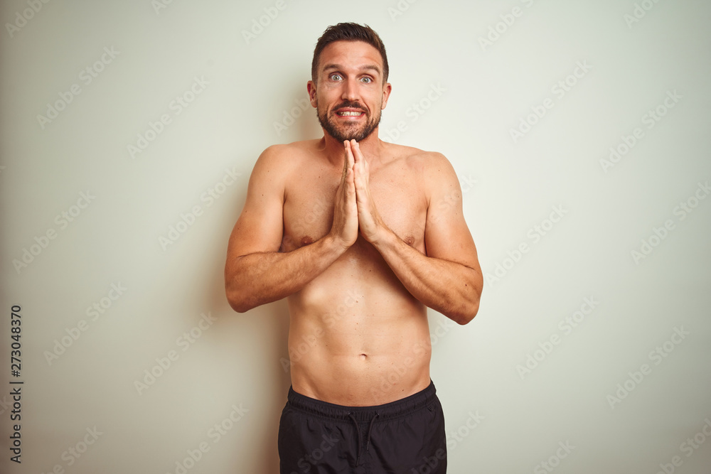 Young handsome shirtless man over isolated background praying with hands together asking for forgiveness smiling confident. Young handsome shirtless man over isolated background praying with hands together asking for forgiveness smiling confident.