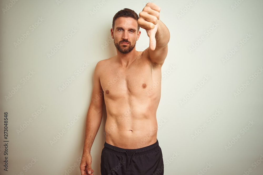 Fototapeta premium Young handsome shirtless man over isolated background looking unhappy and angry showing rejection and negative with thumbs down gesture. Bad expression.