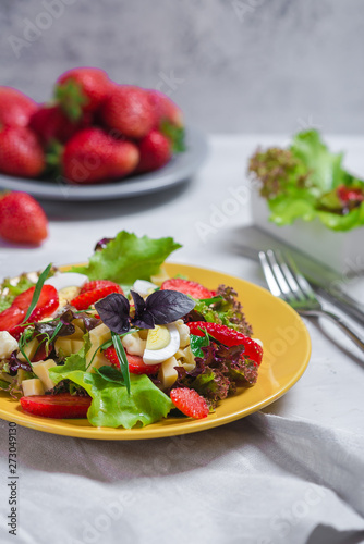 Juicy appetizer with crispy salad, fresh strawberries, cheese and basil, and egg.