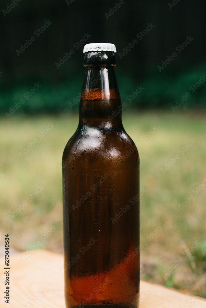 Holding cold beer at garden in hot summer evening