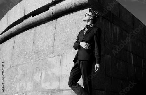 handsome fashion male model dressed in elegant suit posing outdooe. Long haired Metrosexual. Black and white picture. photo