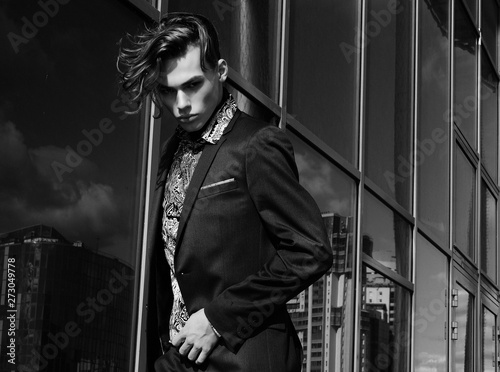 handsome fashion male model dressed in elegant suit posing outdooe. Long haired Metrosexual. Black and white picture. photo