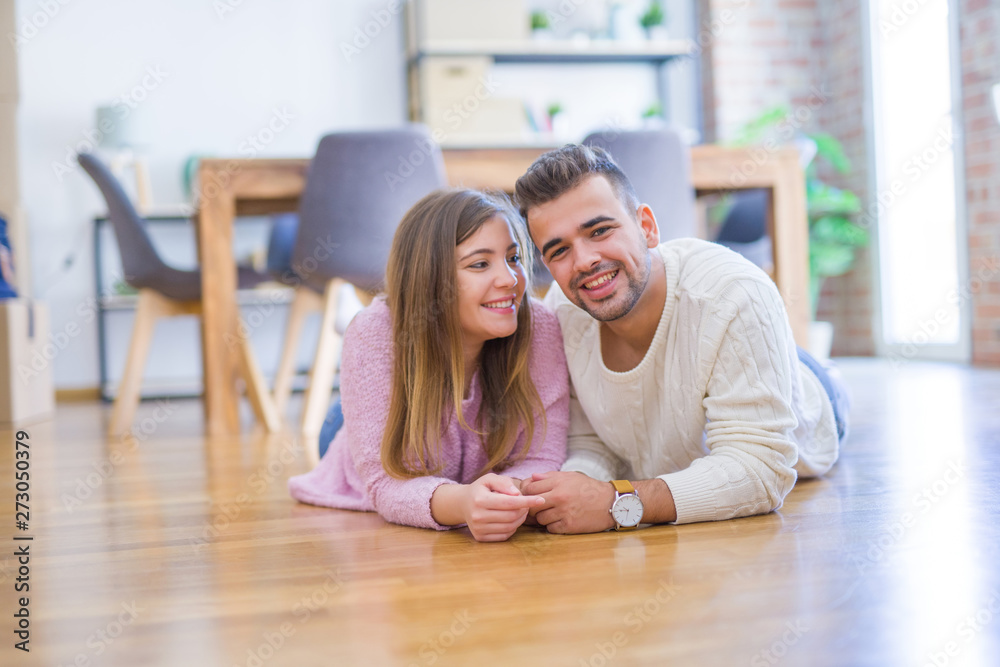 Young beautiful couple in love moving to new home, lying on the floor around cardboard boxes, very happy and cheerful for new apartment Young beautiful couple in love moving to new home, lying on the floor around cardboard boxes, very happy and cheerful for new apartment
