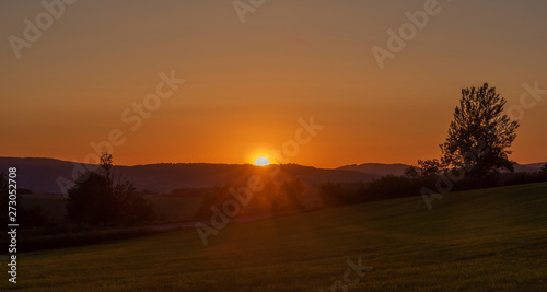 Orange sunset on green grass field near Roprachtice village