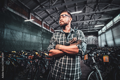 Pensive handsome man crossed his hands is posing at mountain bycicles warehouse.