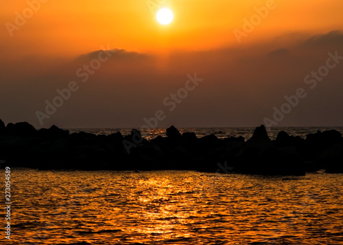 Silhouette of stone coast on a background of sea sunset. Coastline in the evening