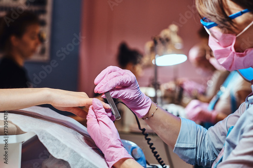 One womas is reciving nail care from another woman, wich is manicurist. photo