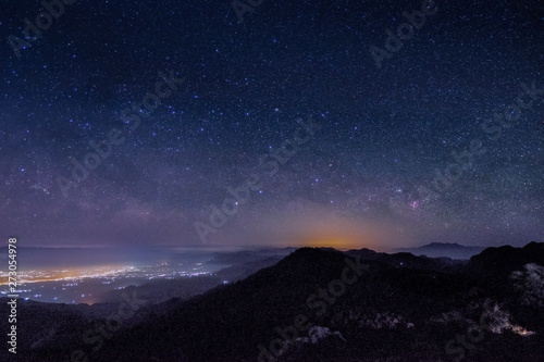 Mountain view morning at night of top hills and city around with soft fog under the stars in dark sky background, Monzone View Point Doi Ang Khang, Chiang Mai, northern of Thailand.