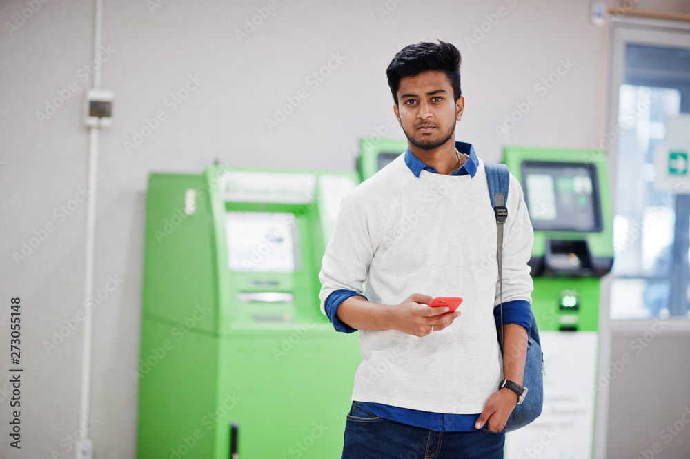 Young stylish asian man with mobile phone and backpack against row of green ATM. Young stylish asian man with mobile phone and backpack against row of green ATM.